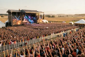 Vue panoramique de la scène principale du festival des Vieilles Charrues avec une foule immense levant les mains